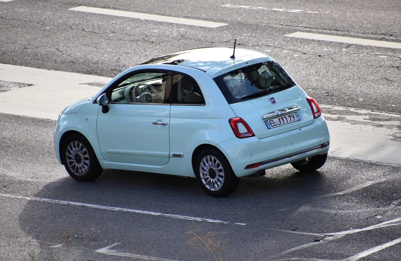 Jasnoniebieski Fiat 500 na miejskiej ulicy