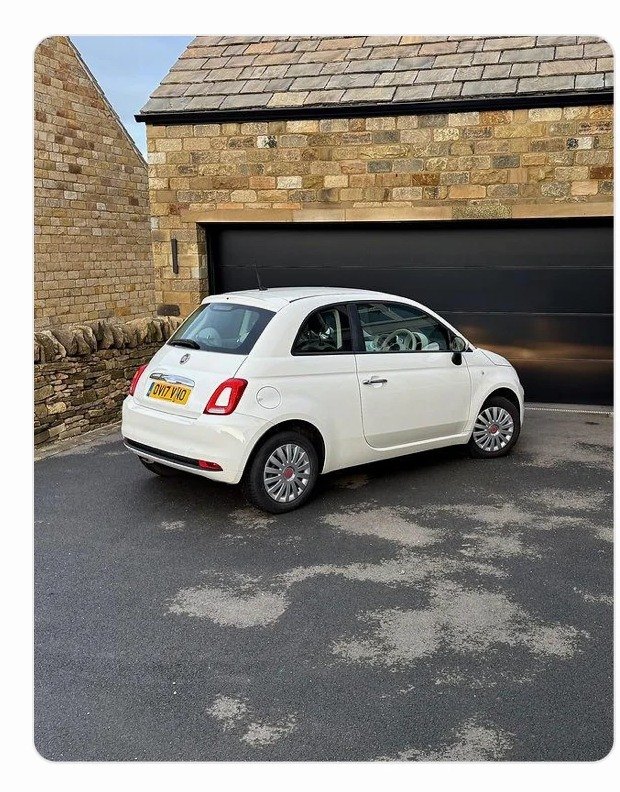 Biały Fiat 500 przed garażem